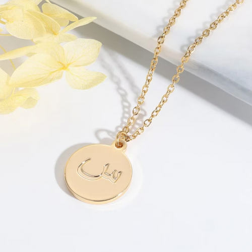 Gold necklace with a round pendant on a white background. Arabic Name Necklace With Stones. gold. rose gold. silver. plated. gold. silver. rose gold. plated 18k solid sterling silver. makana jewellery jewelry