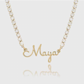 A gold nameplate necklace spelling 'Maya' in cursive script, hanging from a gold chain adorned with clear round-cut stones. Sterling Silver Finish / 18k Gold Plated / 18k Rose Gold Plated / 18k white Gold Plated / 22k Gold Plated. Makana jewellery, jewelry