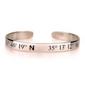 A silver metal cuff bracelet engraved with geographical coordinates, including '31° 46' 19" N' and '35° 13' 12" W', gold plated, sterling silver 925, rose gold plated, imitation jewellery, Makana Jewellery, 18k, jewelry