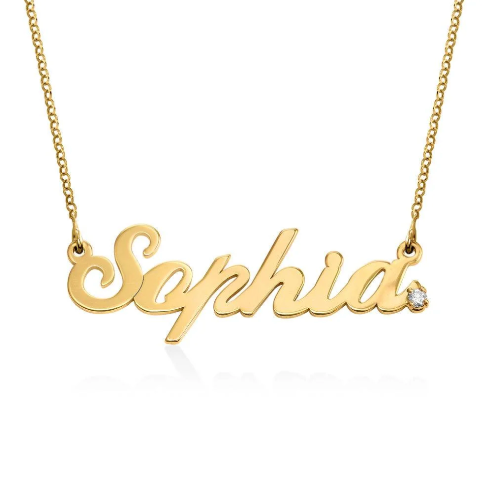 A gold name plate necklace in cursive script, featuring a small clear diamond at the end. Rose gold, sterling silver, plated, makana jewelry, jewellery. gold